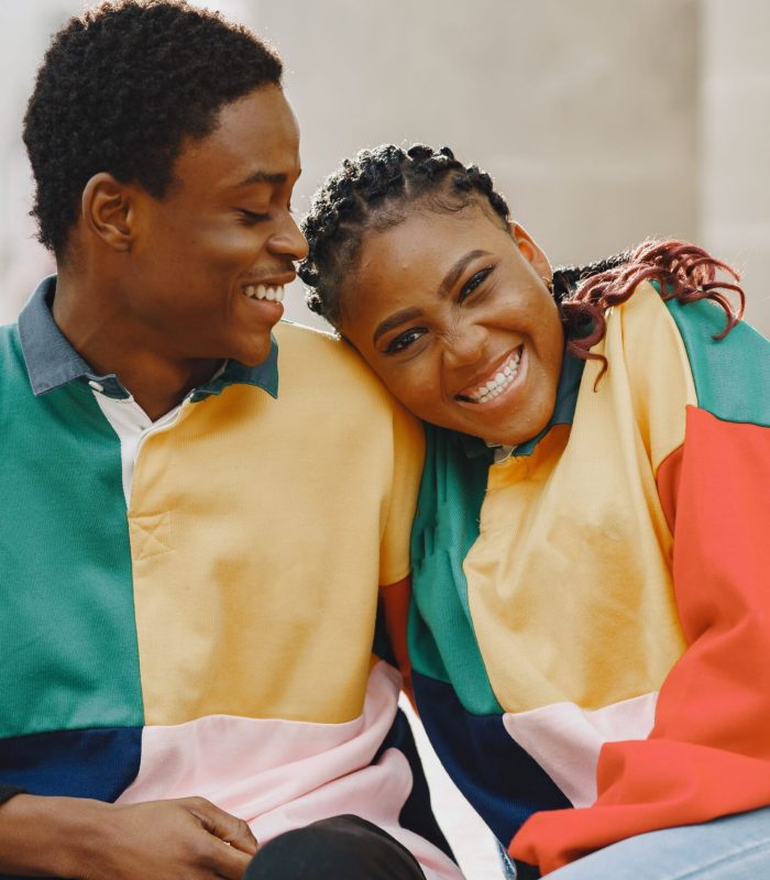 People in identifical clothes. African couple in autumn city. People sitting on a street.